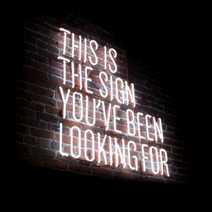 This is the sign you've been looking for, neon sign against dimly lit brick wall, black background, haunted, the haunted hive, life change